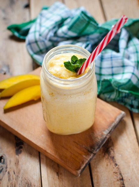 close-up of mango smoothie in a jar on wooden table