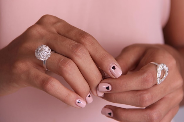 Photo close up of manicured hands with silver rings made with filigree technique