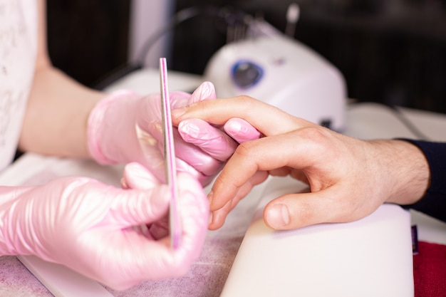 close-up of a manicurist filing person's nails in salon
