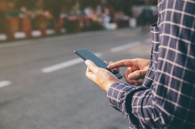 Close-up mannelijke handen met behulp van smartphone op stad winkelstraat, zoeken of sociale netwerken concept,