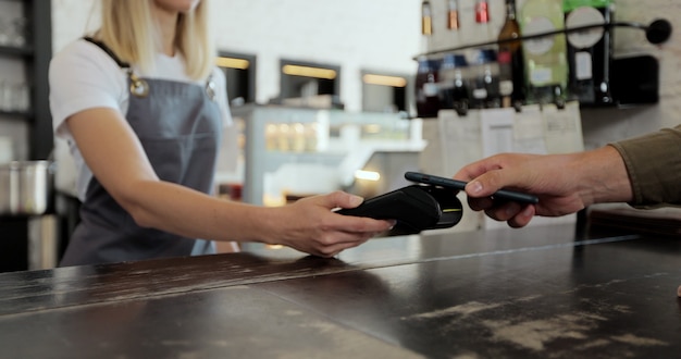 Close-up mannelijke klant betaalt met contactloze NFC-betalingstechnologie op smartphone aan barista