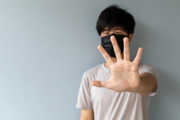 Close-up mannen die een masker dragen om het coronavirus (COVID-19) en PM2.5-stof te beschermen met handpalm