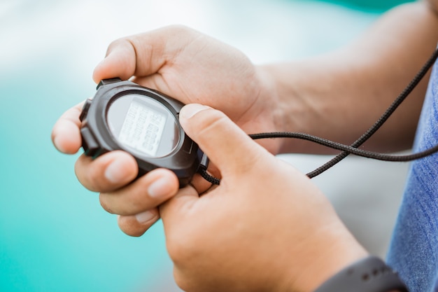 Close up of a mans hand holding and setting a stopwatch