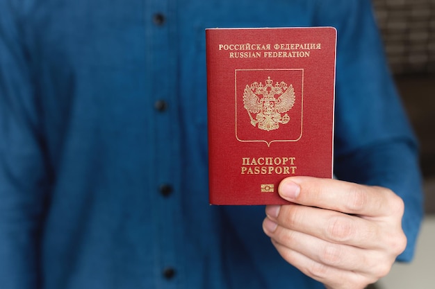 Close-up of a mans hand in a shirt holding a foreign passport the concept of preparing for a