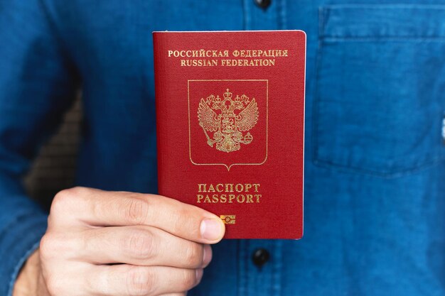 Close-up of a mans hand in a shirt holding a foreign passport the concept of preparing for a