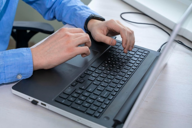 Close up of mans hand typing on laptop keyboard businessman programmer working concept