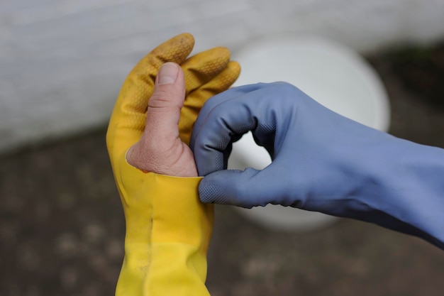 Close-up of mans hand wearing broken yellow gloves