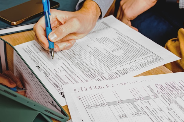 Close-up of mans hands filling us individual tax forms accounting tax season