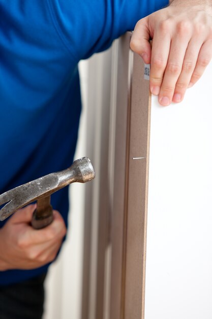 Close-up of a manual man building furniture using a hammer and a nail