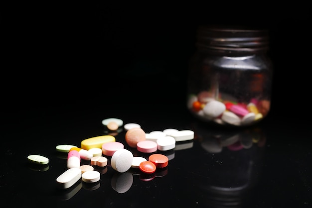 Close up of many colorful pills and capsules on black background