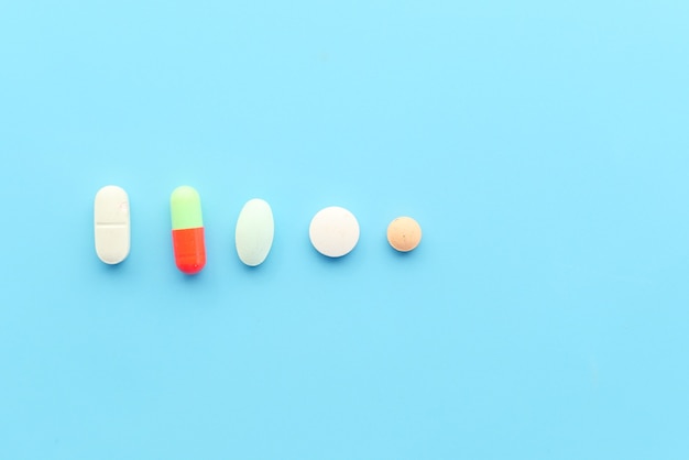 Close up of many colorful pills and capsules on blue background