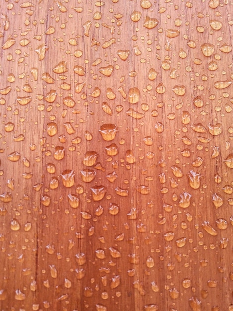 Foto chiuda su molte gocce di acqua sul fondo di legno impermeabile del pavimento