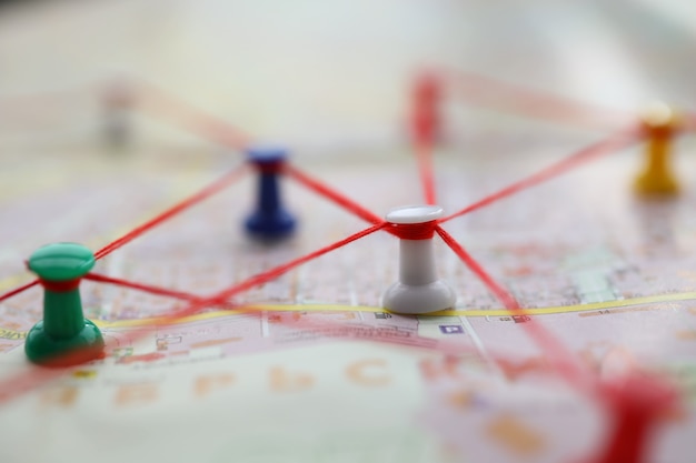 Close-up of map marked with red thread paths of movement. Plan of street with buttons forming route. Pedestrian building route around city. Navigation concept