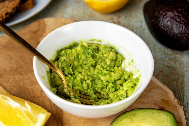 Close up of mashed avocado in a plate with fork on cooking\
table