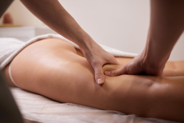 Close-up masseur handen gieten massageolie aan vrouwelijke rug die zich voorbereidt op een ontspannende of revitaliserende massage.