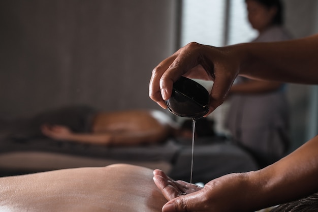 Photo close-up of masseur pouring aroma oil in hand