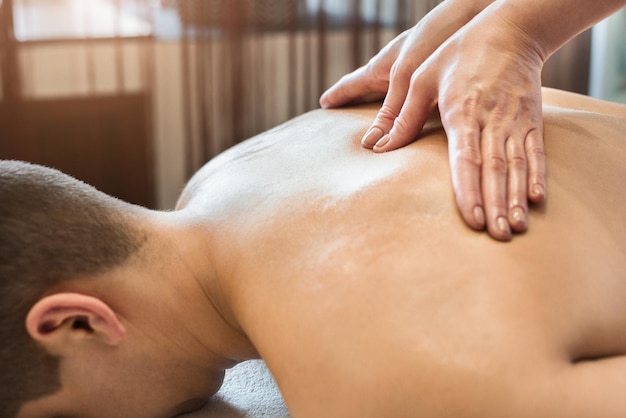 Close-up of masseur's hands and a client's back in spa center