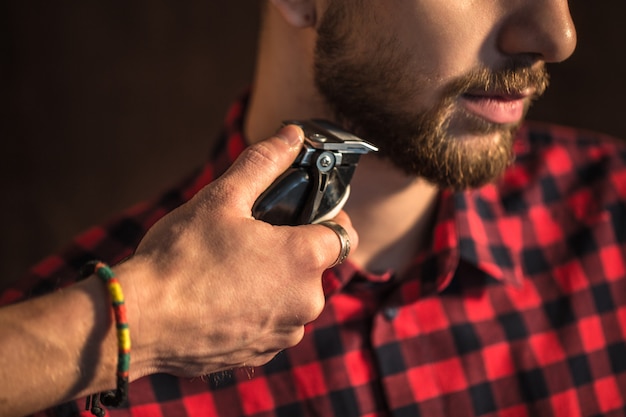 Close-up of Master cuts hair and beard of men