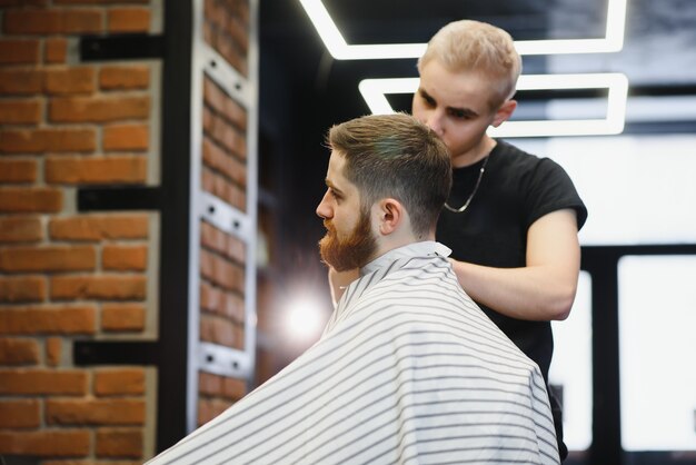 Close-up, master hairdresser does hairstyle and style with scissors and comb.