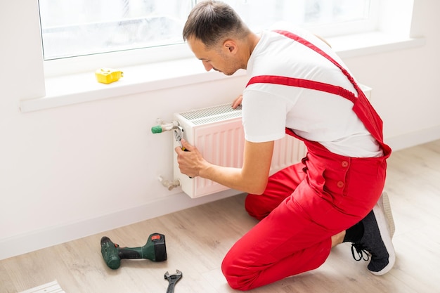 Close-up of mature mechanic hands repairing heating\
system.