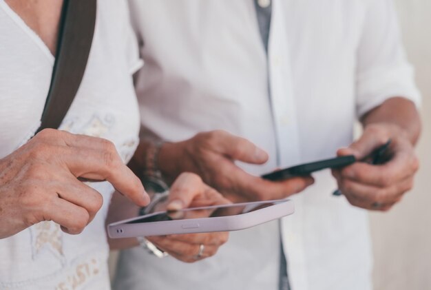 Close up on mature senior people hands typing on their mobile phones concept of modernity