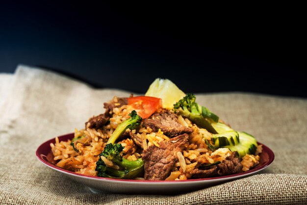 Photo close-up of meat and rice in plate on table