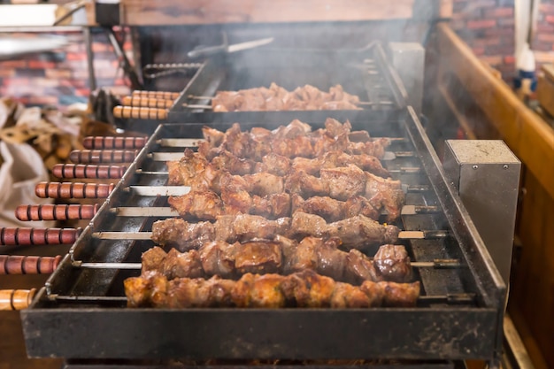 屋外の喫煙バーベキューグリルで熱い石炭の上で調理する肉の串焼きのクローズアップ