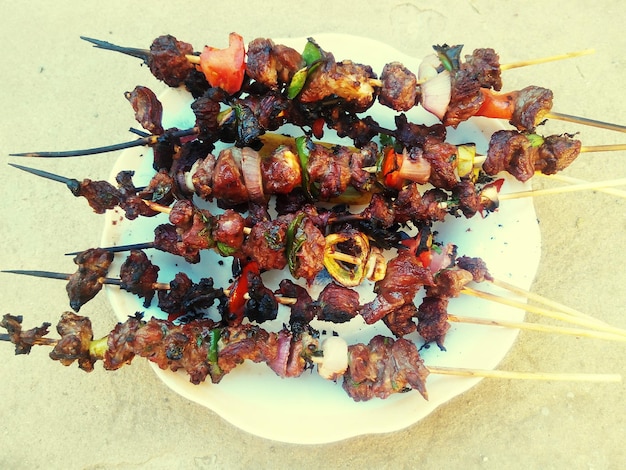 Photo close-up of meat skewers served in plate on table