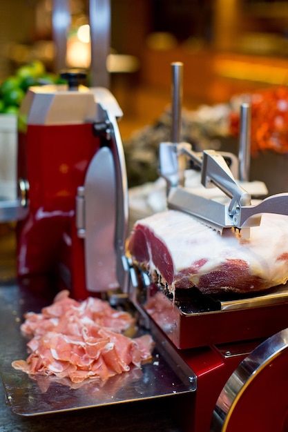 Foto prossimo piano della carne e della macchina per tagliare le fette sul tavolo