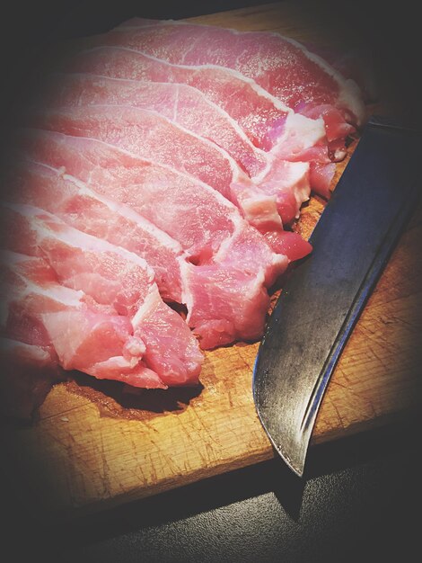 Foto close-up di carne con un coltello sul tavolo da taglio