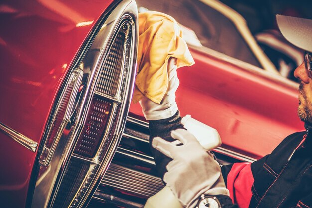 Close-up of mechanic cleaning red car in workshop