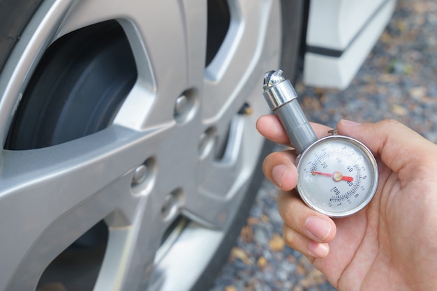 Close up of mechanic hands checking tire pressure using gauge