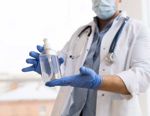 Foto primo piano di un medico che tiene un disinfettante per le mani