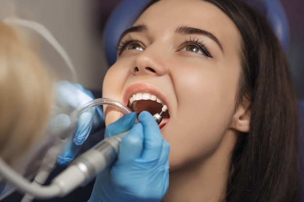 Close-up medical dentist procedure of teeth polishing. Dentist making professional teeth cleaning female young female patient at the dental office. Close-up plan