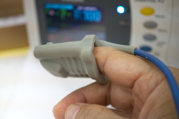 Photo close-up of medical equipment on finger at hospital