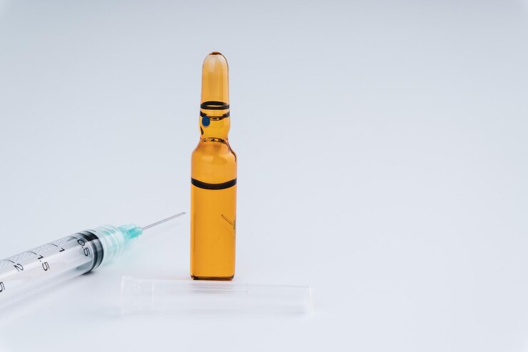 Photo close-up of medicine bottle and syringe against white background