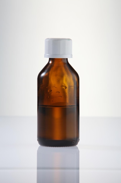 Photo close-up of medicine in bottle on table against white background