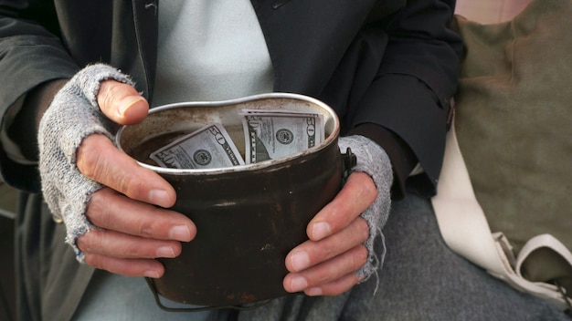 Close-up of men's hands holding financial aid, dollars. Homeless, old man holding dollars in his hand