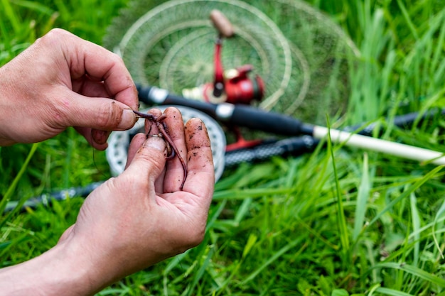 Close up Men's hands put bait on hook to fish with fishing rod Lifestyle recreation leisure concept Fisherman with worm