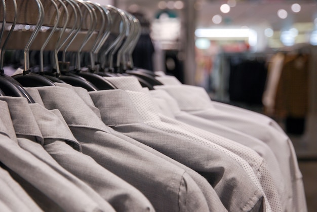 Close up of men's shirts of neutral tones on hanger in clothing store