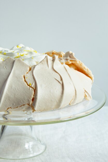 Close-up of meringue cake Pavlova with whipped cream and lemon. Crusty dessert.