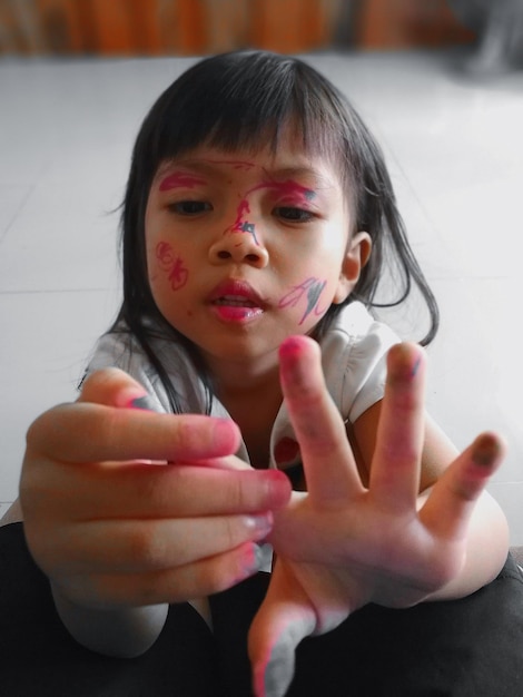 Photo close-up of messy girl with paint sitting at table