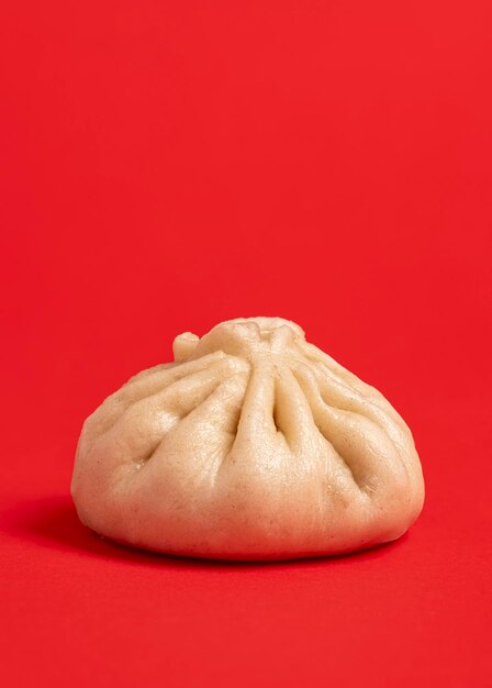 Foto close-up met een enkele bao dumpling geïsoleerd op een rode achtergrond zelfgemaakte bao met vlees