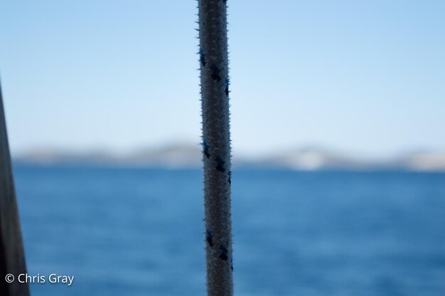 Close-up of metal against sea against clear sky
