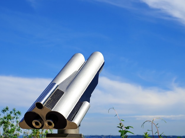 Close up metal binoculars on background viewpoint overlooking the blue sky with clouds Touristic telescope