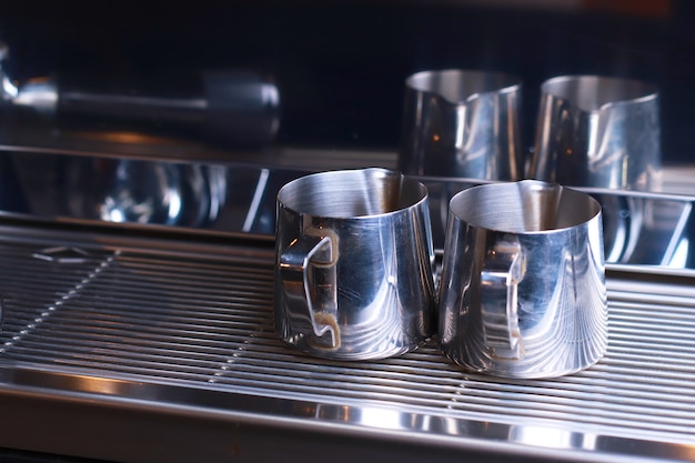 Close-up, metal coffee mugs stand on a grid in the coffee machine