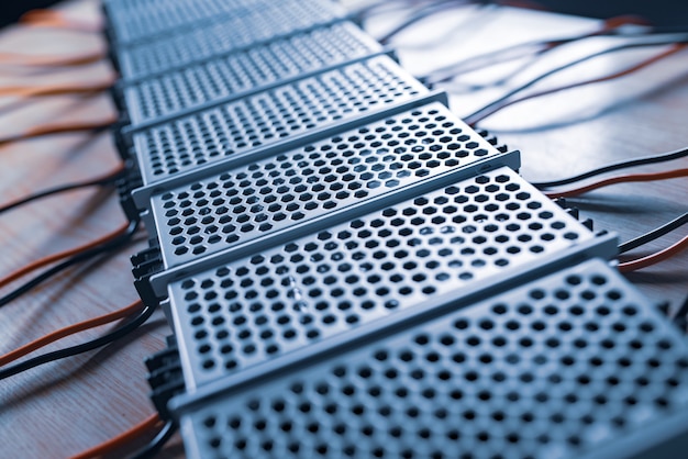 Close up of the metal mesh cases of power supply and wires are on a wooden table at the production of high-tech computers. Concept High Tech and Computer