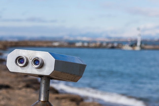 Close-up metalen verrekijker voor openbaar gebruik met uitzicht op de prachtige haven en de zee