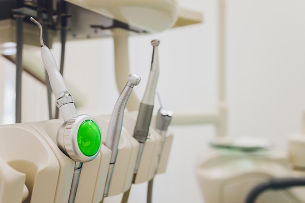 Close up of the metallic dentist tools with blue dentist chair on the background