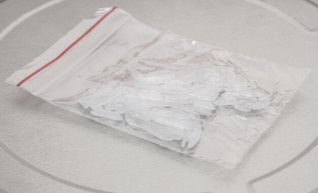 白い背景のプラスチック袋の中のメタンフェタミンのクローズアップ